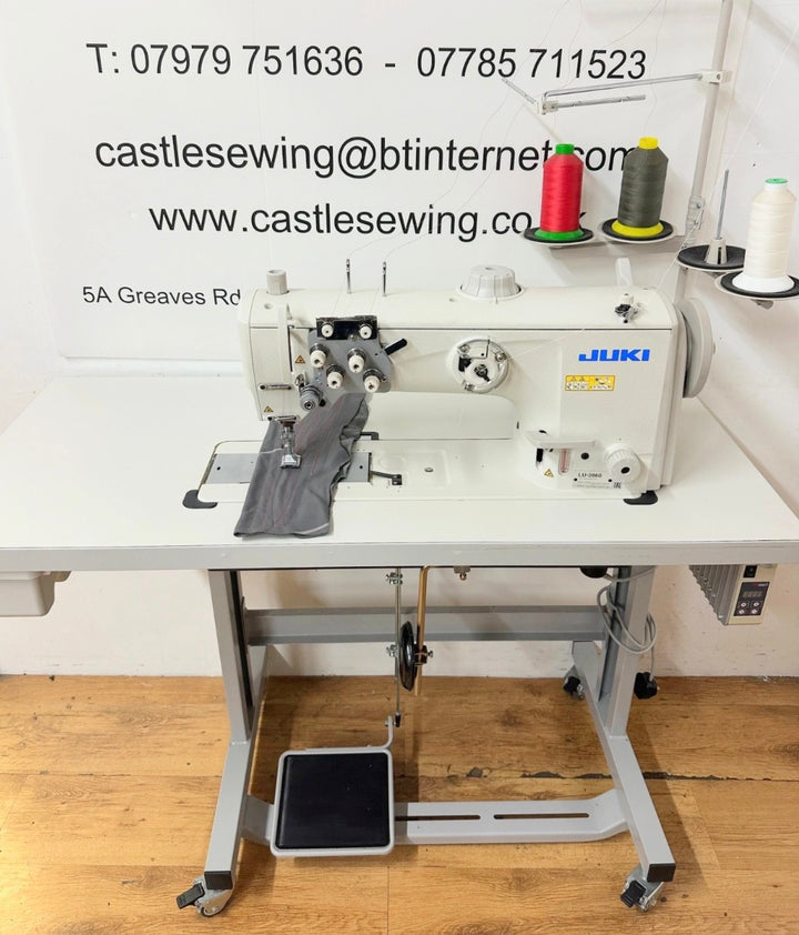 Juki sewing machine on a white table with contact information displayed.